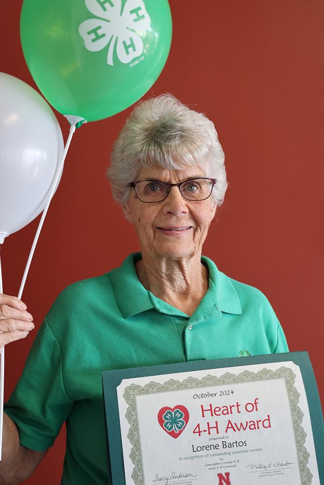 Lorene Bartos holding certificate and balloons